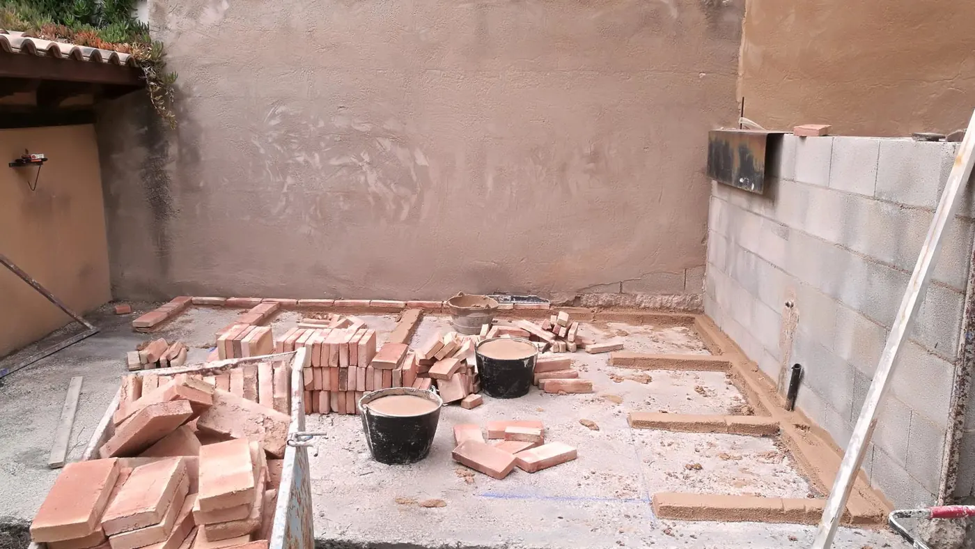 El patio durante la obra, con el ladrillo preparado para levantar la barbacoa