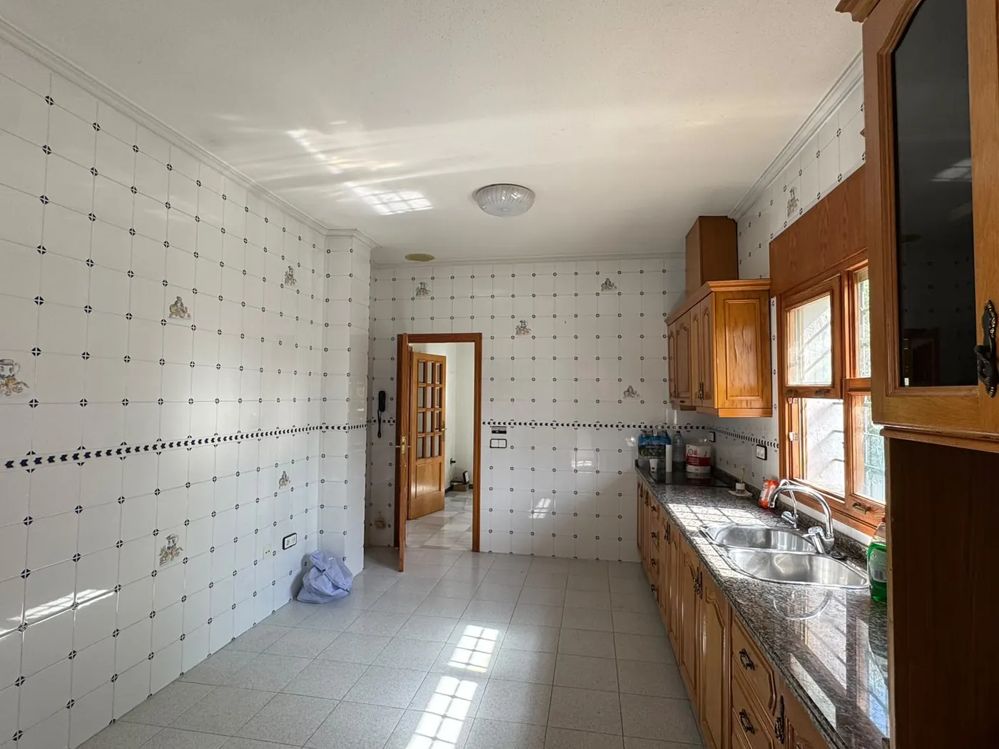 La cocina antes de la reforma, con muebles de madera y azulejo decorado