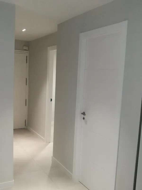 El mismo pasillo terminado, con puertas blancas y suelo claro